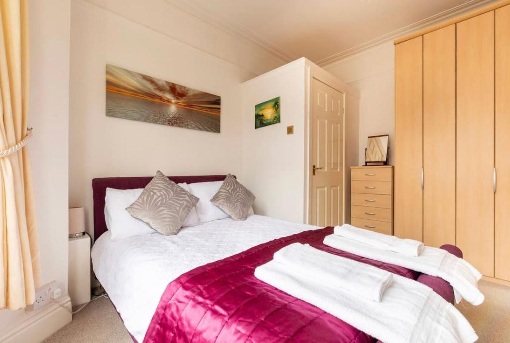 a bedroom with a large bed with a pink blanket at Shelley’s Seaside Stay (Garden/ Double Drive) in Porthcawl