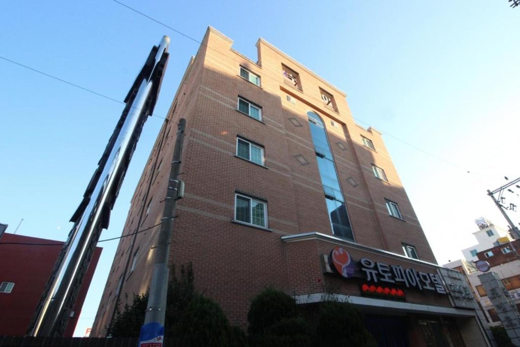 a tall brick building with a sign in front of it at Utopia Hotel in Gumi