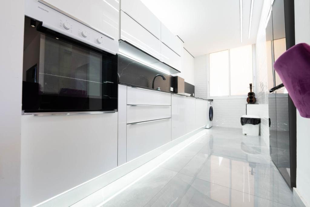 a kitchen with white cabinets and a large window at New! luxus- Best suit 2 minutes fromTel Aviv in Bat Yam