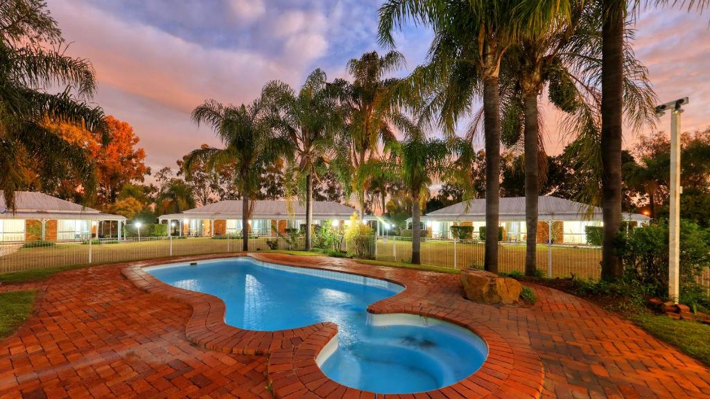 a swimming pool in a yard with palm trees at Chinchilla Great Western Motor Inn in Chinchilla