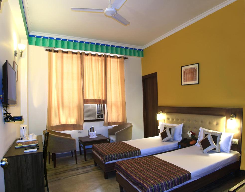 a hotel room with two beds and a table at Inn Tawang Near B L Kapoor Hospital A Well Hygiene Hotel in New Delhi
