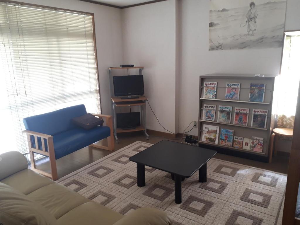 a living room with a couch and a table and a tv at Guest House Nagasaki Vogelnest in Nagasaki