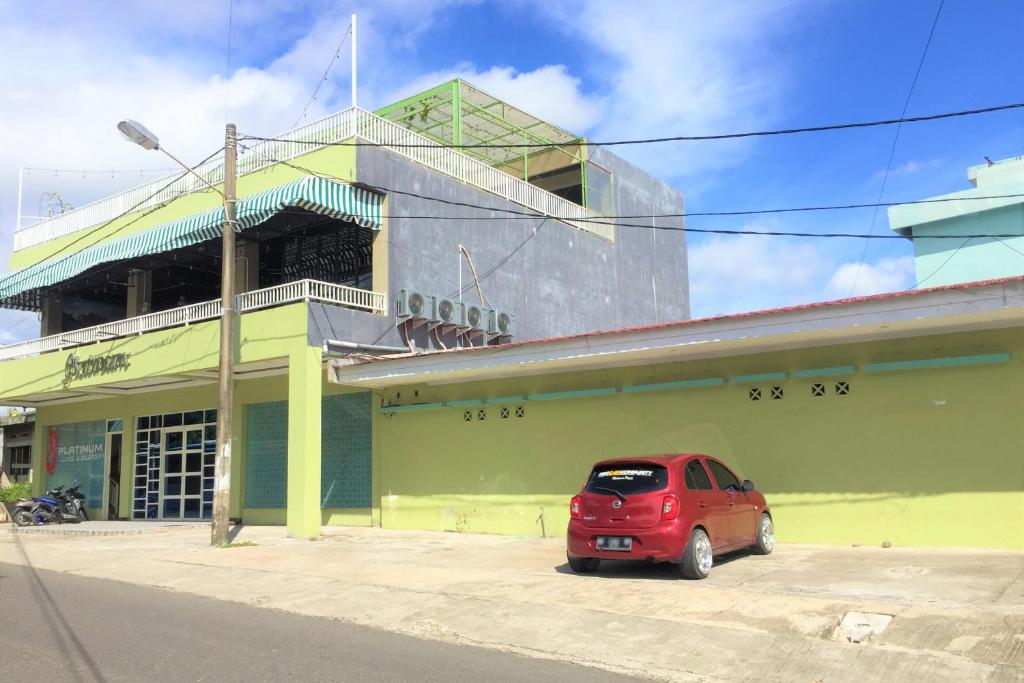 a red car parked in front of a building at Urbanview Hotel Platinum Parepare in Parepare