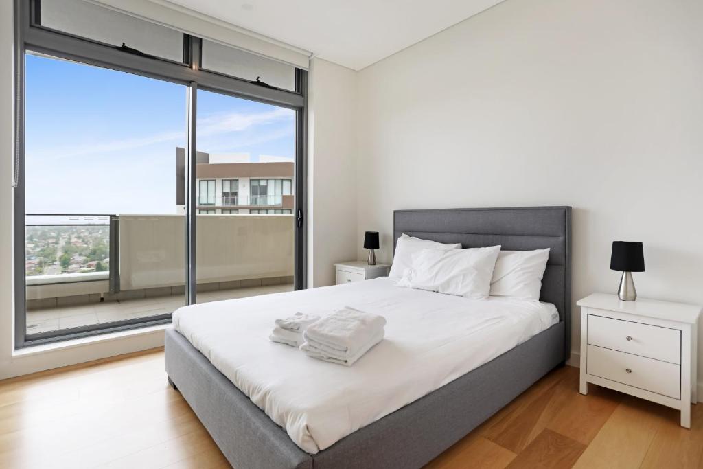 a bedroom with a bed and a large window at KULA Macquarie Park in Sydney