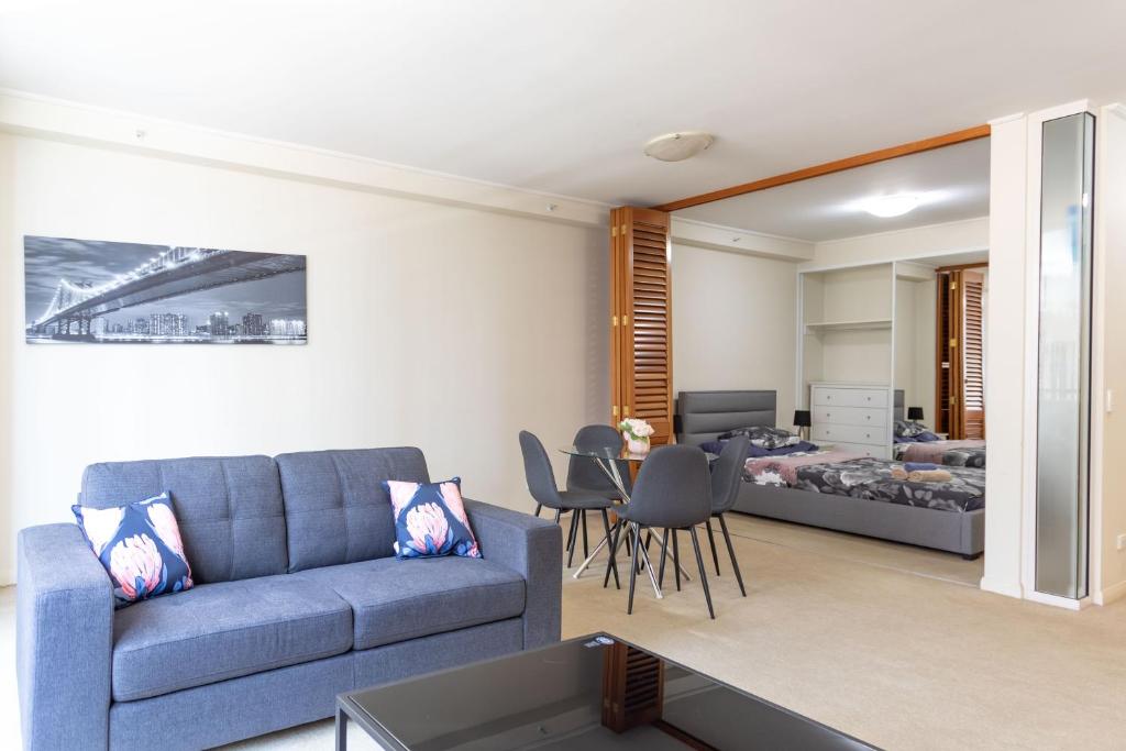 a living room with a blue couch and a bedroom at KULA North Sydney-Napier in Sydney