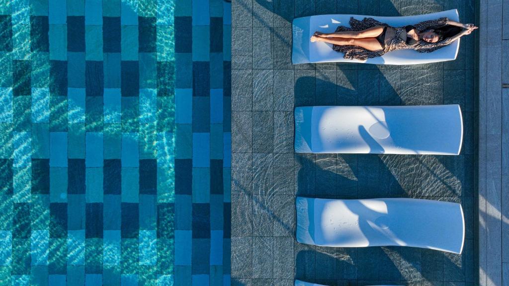 a woman laying on a chair next to a swimming pool at HVD Reina del Mar - Premium Spa Service & Free Parking in Obzor