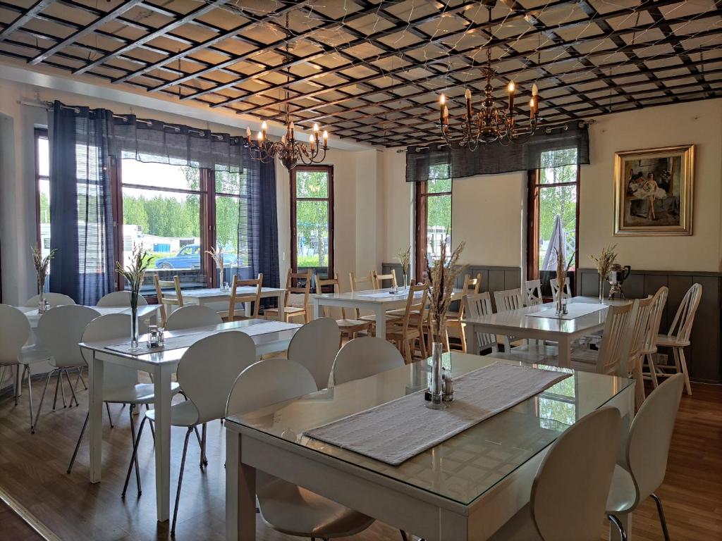 uma sala de jantar com mesas, cadeiras e janelas em Hotelli Patruuna em Imatra