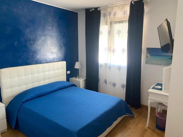 Dormitorio azul con cama y ventana en Blue Sea Rooms Apartment Cagliari, en Cagliari