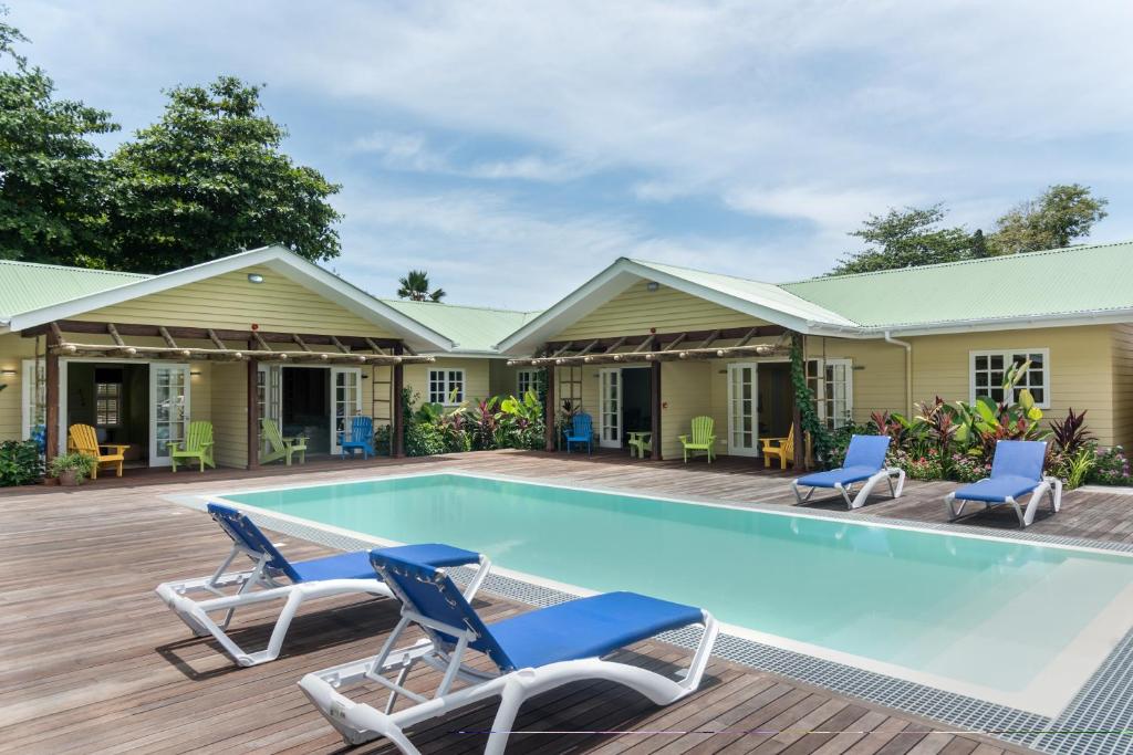 a swimming pool with chairs and a house at Residence Praslinoise in Grand'Anse Praslin