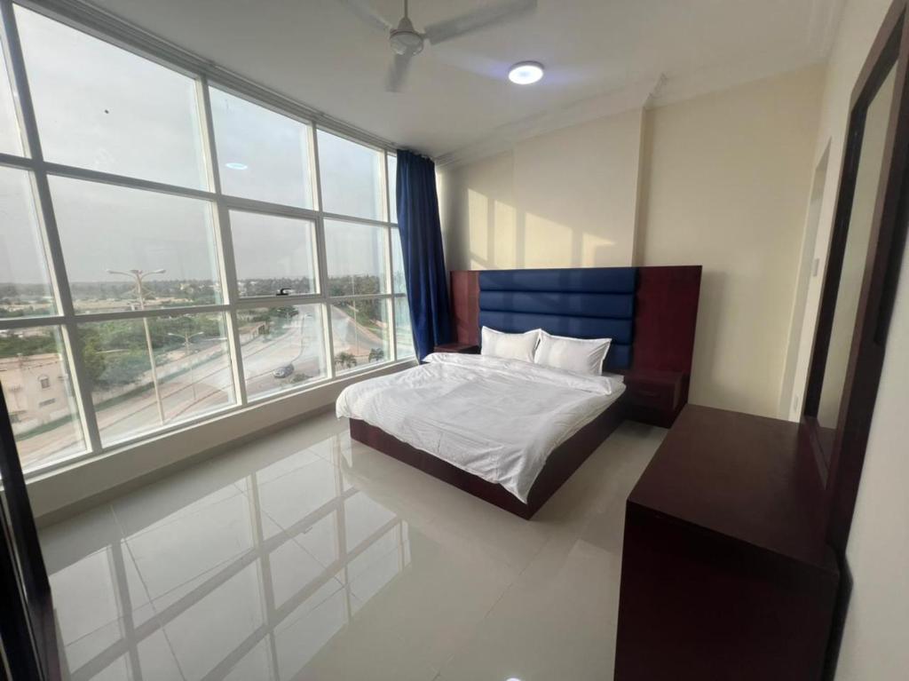 a bedroom with a bed in a room with windows at RED-25 - Razat Alard 4 in Salalah