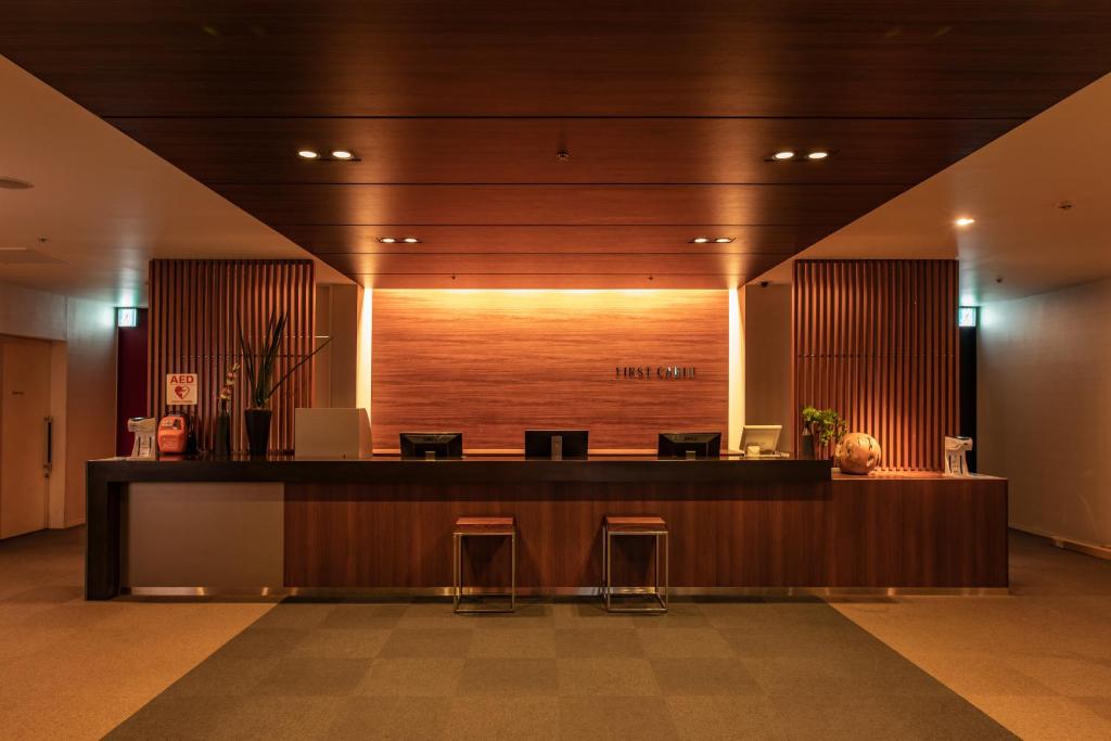 eine Lobby mit einer Rezeption und Hockern in einem Gebäude in der Unterkunft First Cabin Haneda Terminal 1 in Tokio