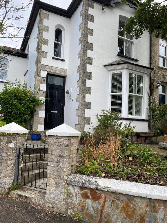 uma casa branca com uma porta preta e um portão em Devonshire Terrace B&B em Truro