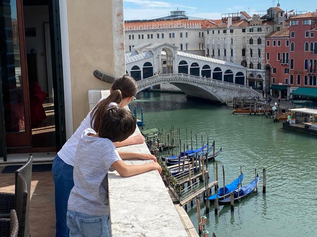 Eine Frau und ein Kind, die über eine Brücke über einen Fluss schaute. in der Unterkunft Ve-nice Suite Rialto SP720-4 in Venedig