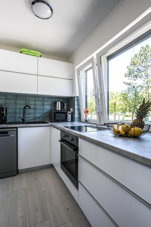 kuchnia z białymi szafkami i miską owoców na ladzie w obiekcie Dream Summer House Fonyód w mieście Fonyód