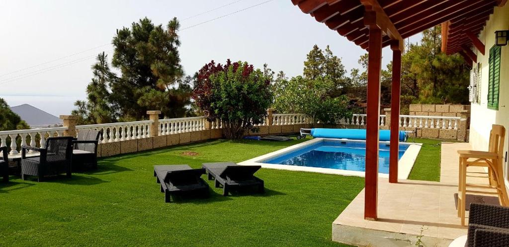 a backyard with a pool and chairs and a fence at Seaview Chalet in Arafo