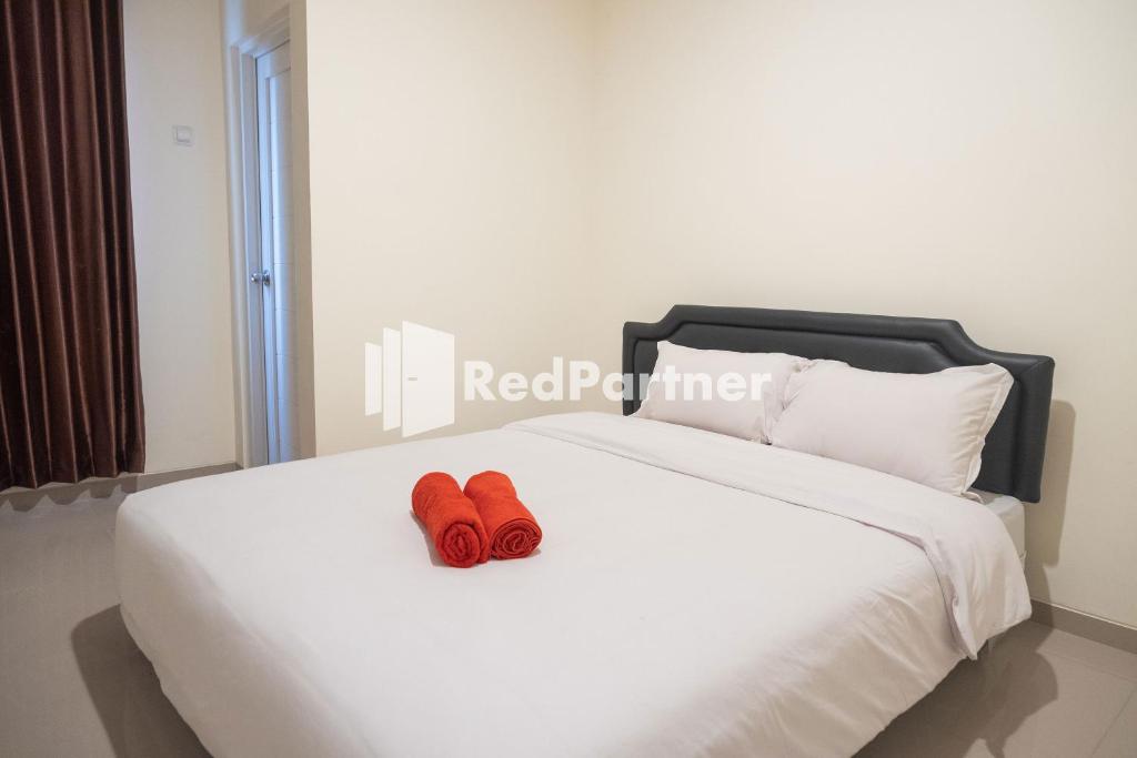 a pair of red shoes sitting on a white bed at RedDoorz at Astana Malioboro in Yogyakarta