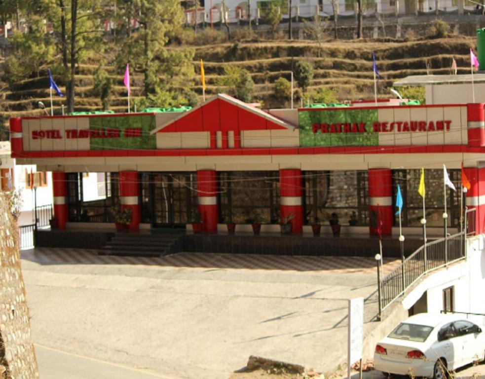 un edificio rosso e bianco con un'auto parcheggiata in un parcheggio di Travellers Lodge by StayApart a Bhowāli