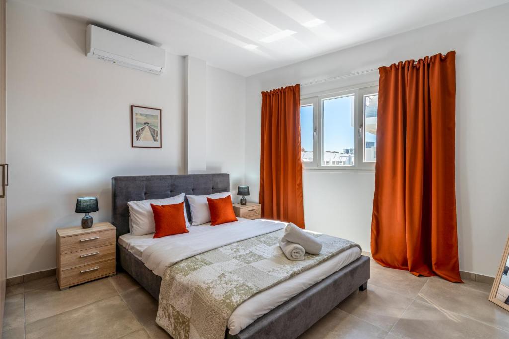 a bedroom with a bed with orange curtains and a window at Olive 2-Bedroom Apartment in Larnaca in Larnaka