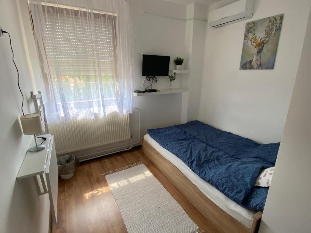um pequeno quarto com uma cama e uma janela em Panda Vendégszállás em Jászberény