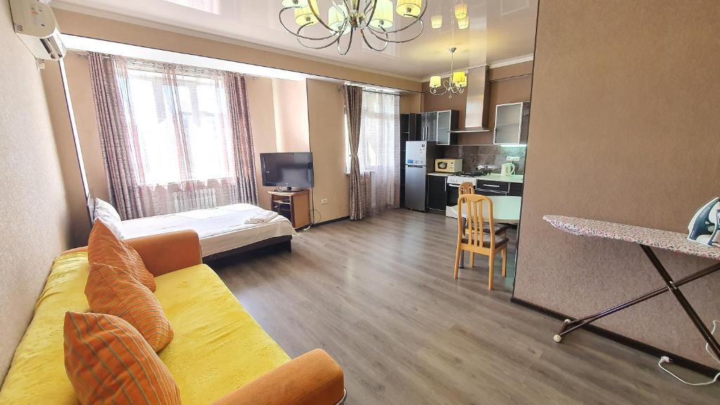 Una sala de estar con un sofá y una cocina. en Orange apartment with panoramic view, en Bishkek