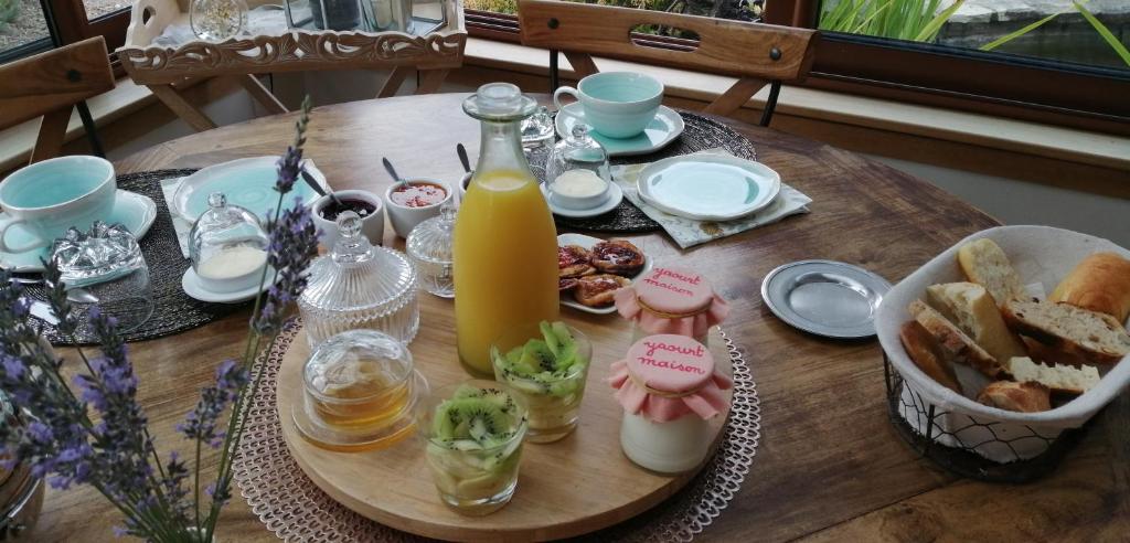 a table with a tray of food and a bottle of orange juice at L&#39;Orme Seul, Maison d&#39;hôtes in Vineuil