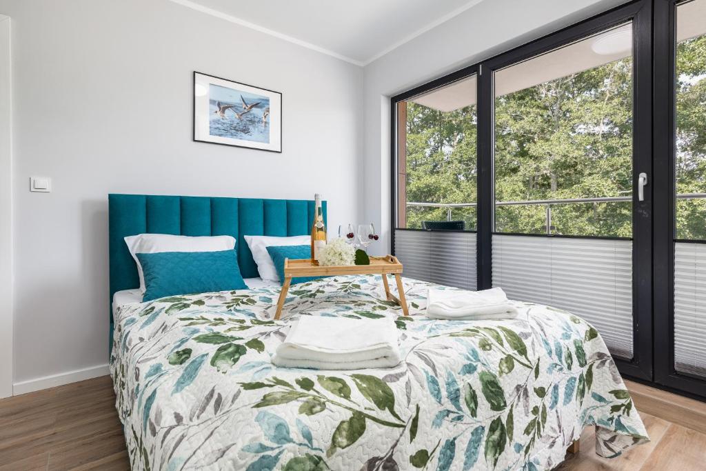 a bedroom with a bed with a green headboard at Little Laguna Apartments Sauna & Parking by Renters in Międzywodzie