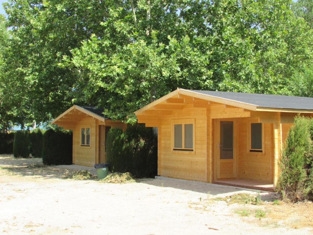 una pequeña casa de madera con árboles en el fondo en Camping Hoces de Mira en Mira