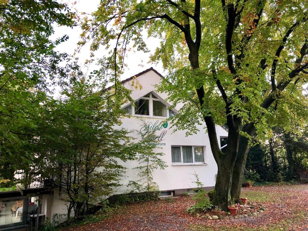 ein weißes Haus mit einem Baum davor in der Unterkunft Silvio-Gesell-Tagungsstätte in Wuppertal