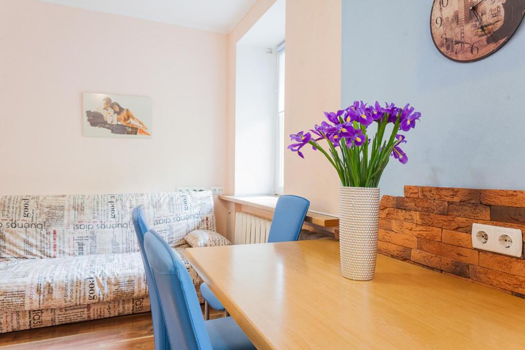 eine Vase lila Blumen auf einem Holztisch in der Unterkunft Cozy apartments near Olympic Stadium in Kiew