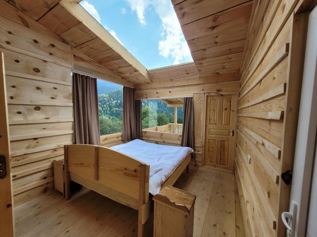 uma cabina de madeira com uma cama e uma janela em Ecohouse Svaneti em Mestia