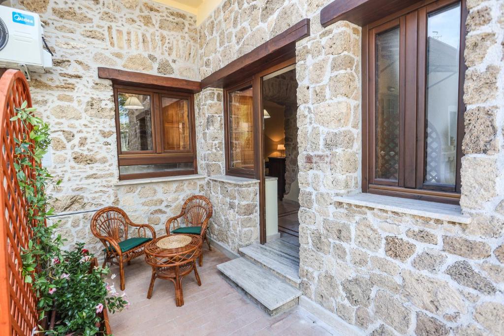 a patio with chairs and a table and windows at Dimora dei Greci in Paestum