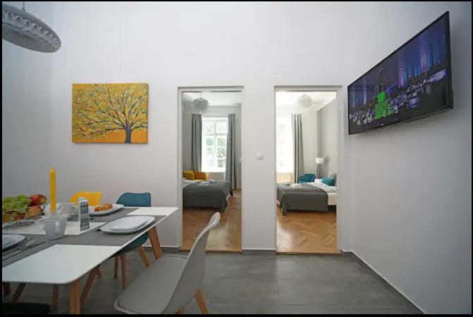 ein Wohnzimmer mit einem Tisch und einem TV an der Wand in der Unterkunft 3bdr/2bath/3A/c design apt, central, free parking, quiet in Budapest