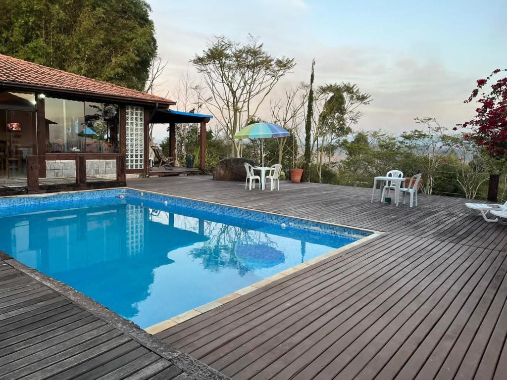a swimming pool with a deck and a house at Recanto Cravo e Canela in Itatiaia