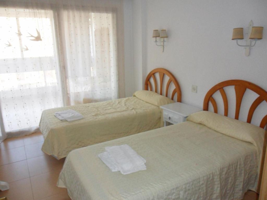a room with two beds and a table and a window at Apartamentos Cervantes in Benidorm