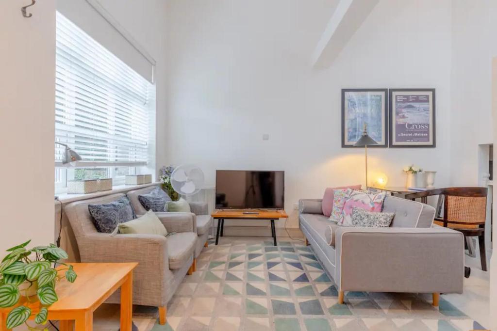 uma sala de estar com dois sofás e uma televisão em Cosy 1 Bedroom Apartment near Wimbledon station em Londres