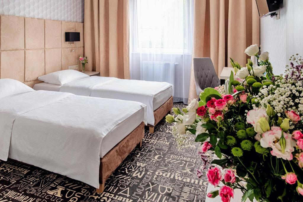 a hotel room with two beds and a bouquet of flowers at Citi Hotel's Warszawa-Falenty in Raszyn