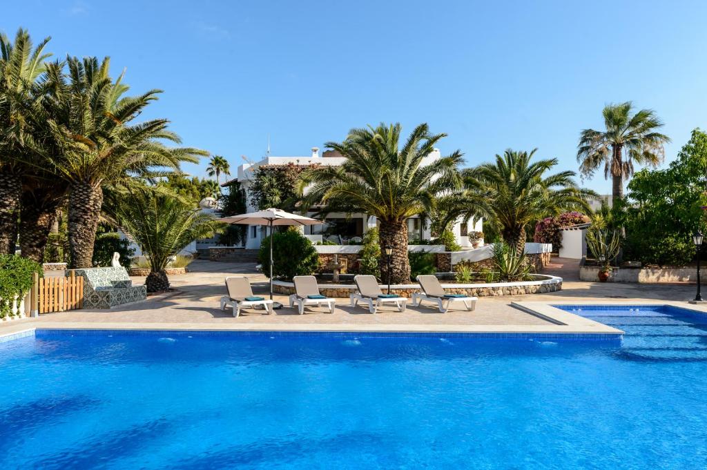 a swimming pool with chairs and palm trees at Villa Can Ravi in Cala de Bou