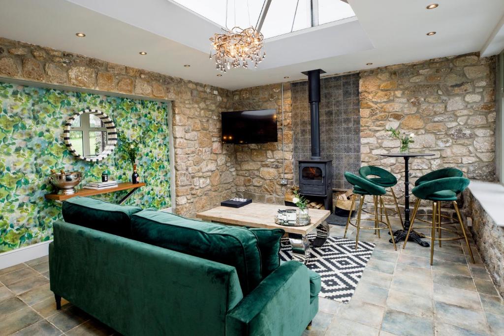 a living room with green furniture and a stone wall at The Forge in Swansea