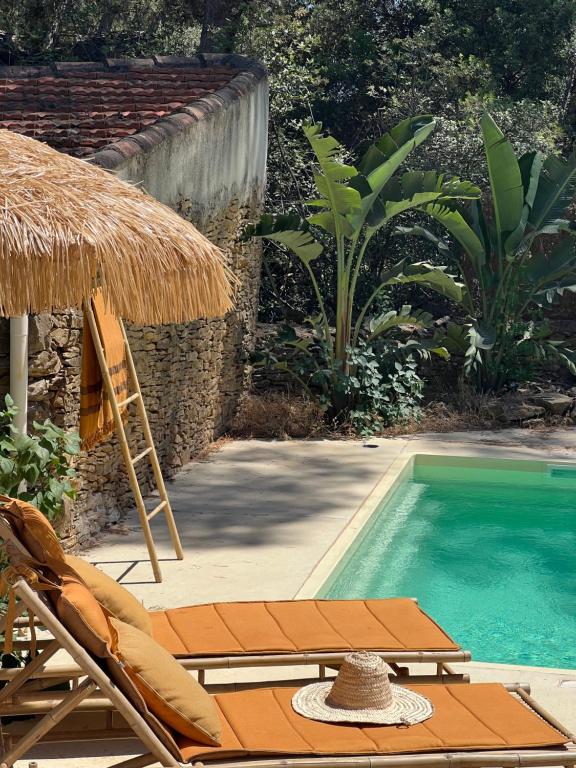 a swimming pool with a straw umbrella and chairs next to a swimming pool at l'Amarantine in La Ciotat