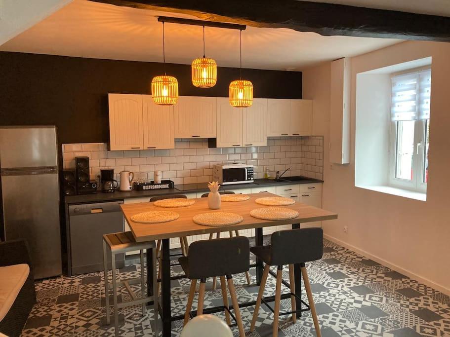 kuchnia ze stołem z krzesłami i lampkami w obiekcie La p’tite maison de locqui w mieście Locquirec