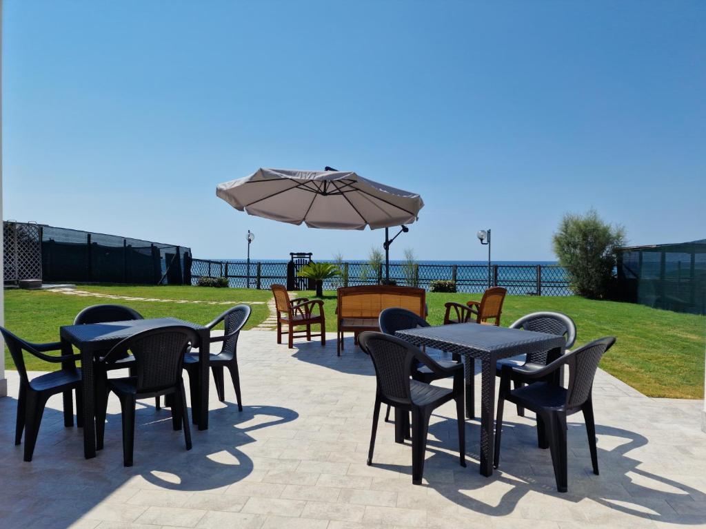 a patio with tables and chairs and an umbrella at Villa Epi in Sperlonga