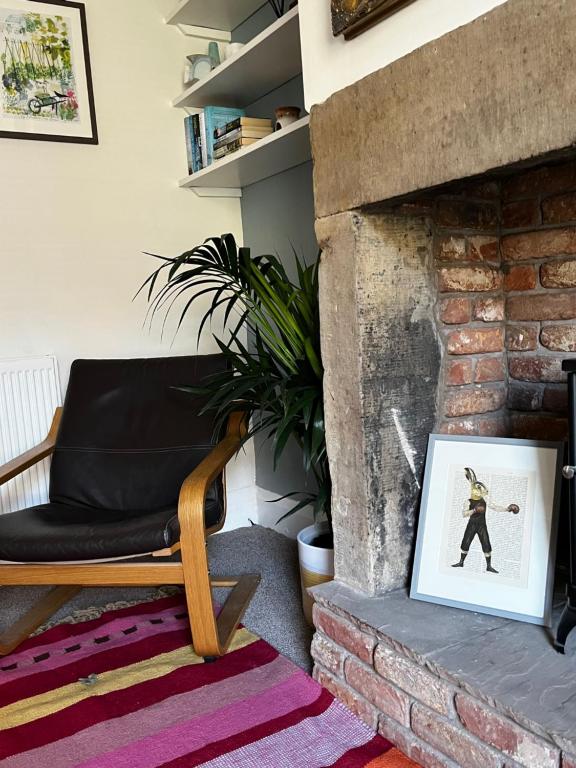 a living room with a chair and a fireplace at Feather and Twigs Cottage, Croston in Croston
