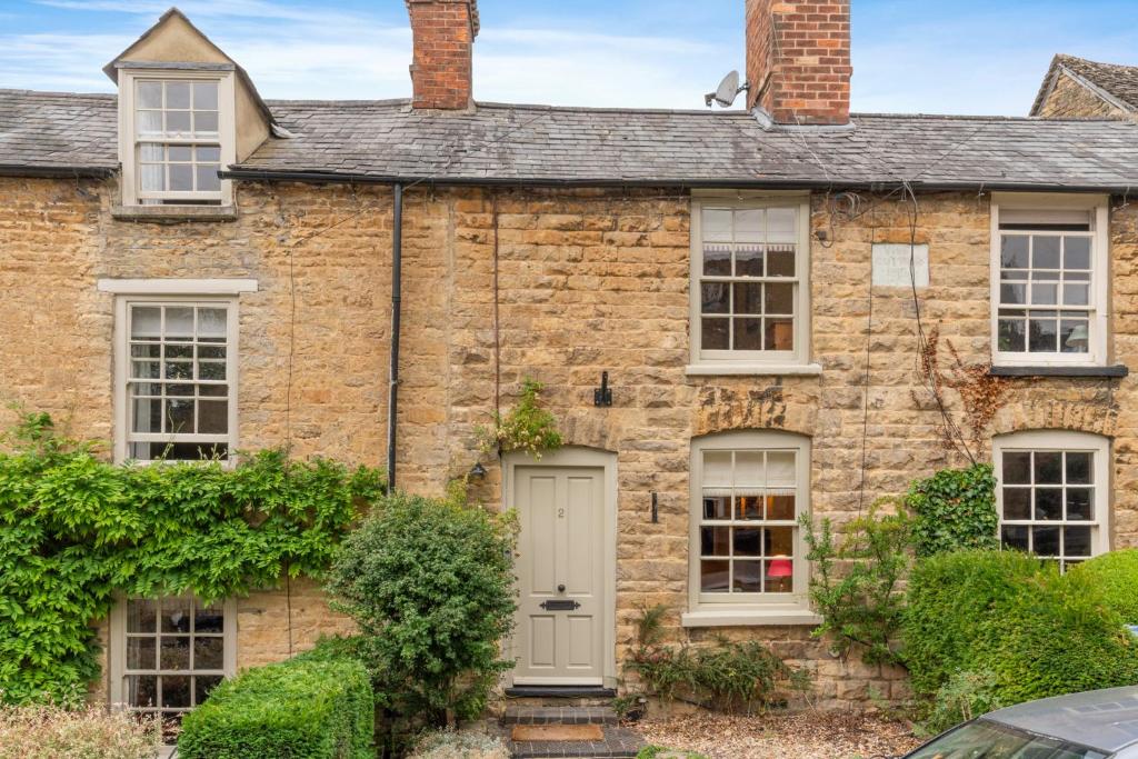an old brick house with a white door at Vine Cottage in Charlbury