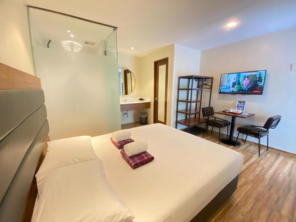 a hotel room with a bed and a desk with a chair at The Hub District Garden Suites in Manila