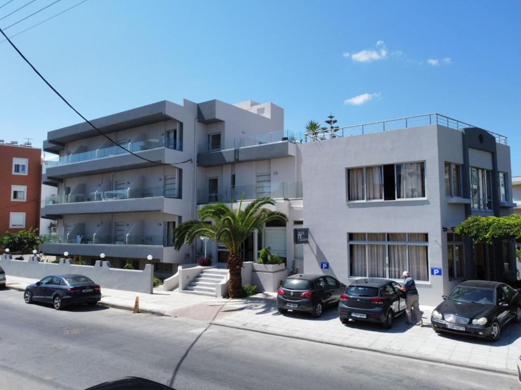 a large white building with cars parked in front of it at Falassarna Hotel in Chania