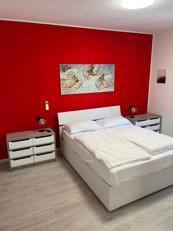 sypialnia z czerwoną ścianą z łóżkiem i 2 stolikami nocnymi w obiekcie Apartment Verdi BARDOLINO w mieście Bardolino