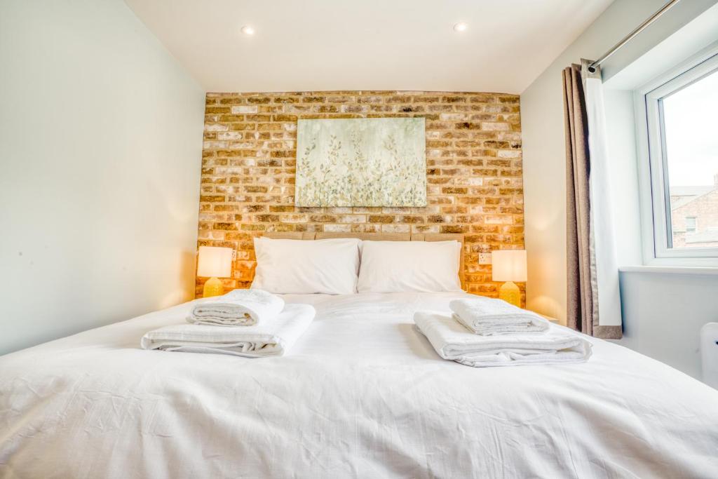 a bedroom with a white bed with a brick wall at Suite 2- 2 Bed Apartment in Lincoln