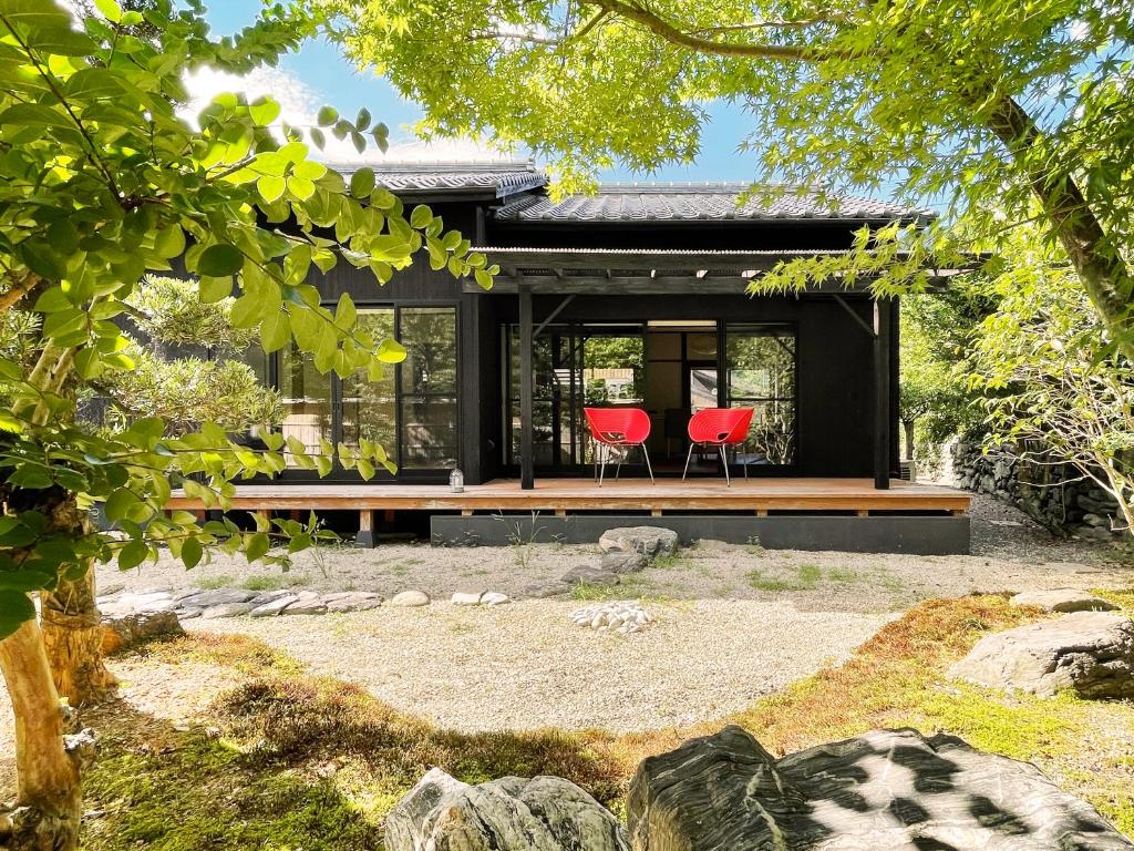 a black house with two red chairs in front of it at Akizuki Niwa (Garden) House in Asakura