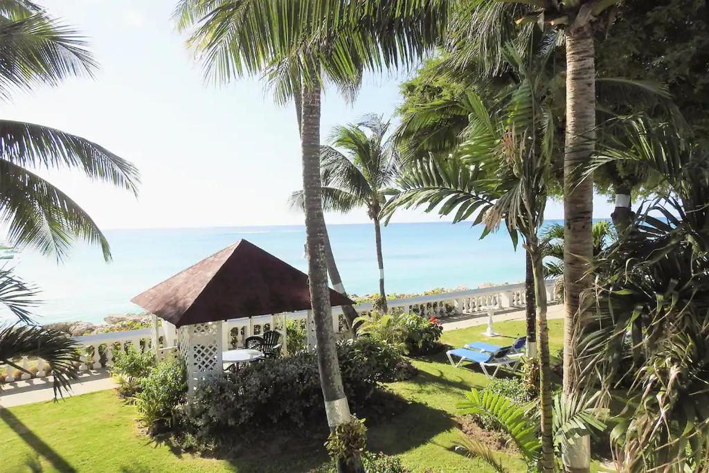 a view of the beach from the balcony of a resort with palm trees at Zenbreak Freshwater Beachfront 6 in Saint Michael