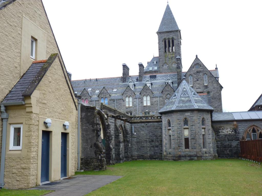 a large stone building with a clock tower at Glenmorangie Highland Club Scotland in Fort Augustus